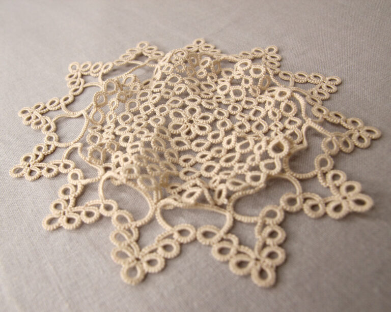 Wavy tatting doily with rippling edges caused by too many rings in outer rounds